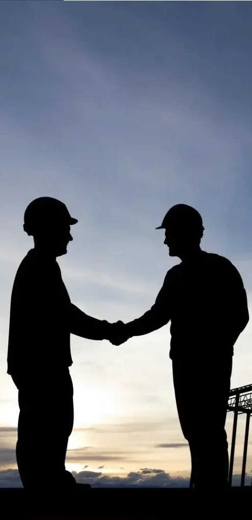 Two professionals shaking hands at a construction site